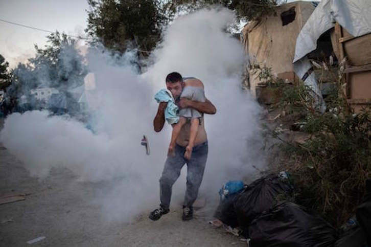 Un refugiado trata de poner a salvo a su hijo en Moria. (Angelos TZORTZINIS/AFP)