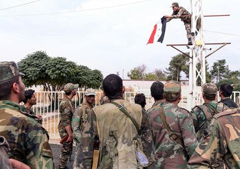 Soldados sirios izan la bandera del régimen en la ciudad kurda de Kobane. ( AFP SANA) 