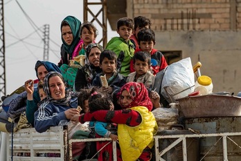 Mujeres y niños huyen de Serekaniye en la caja de un camión. (Delil SOULEIMAN / AFP)