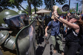 Manifestantes ante una barrera policial en Santiago de Chile. (CLAUDIO REYES / AFP) 