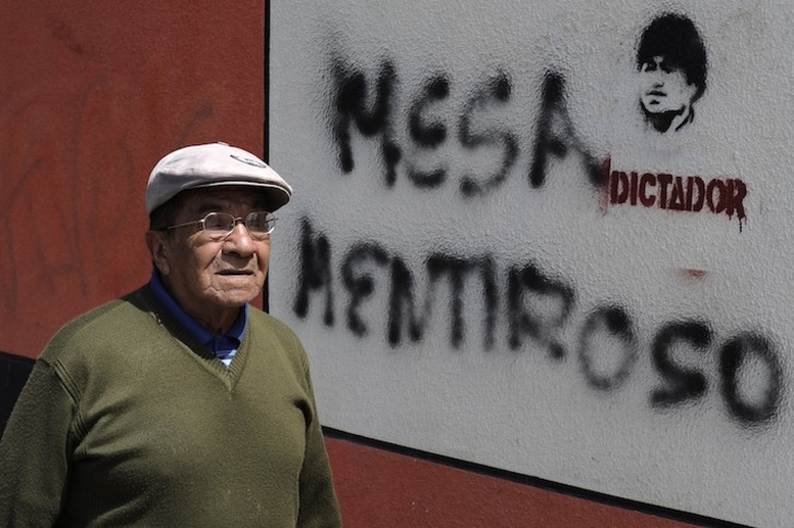 Un hombre camina ante sendas pintadas que muestran el polarizado clima poselectoral en Bolivia. (Jorge BERNAL / AFP)