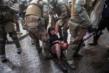 Carabineros detienen a una joven herida en Santiago de Chile. (Claudio Reyes/ AFP)