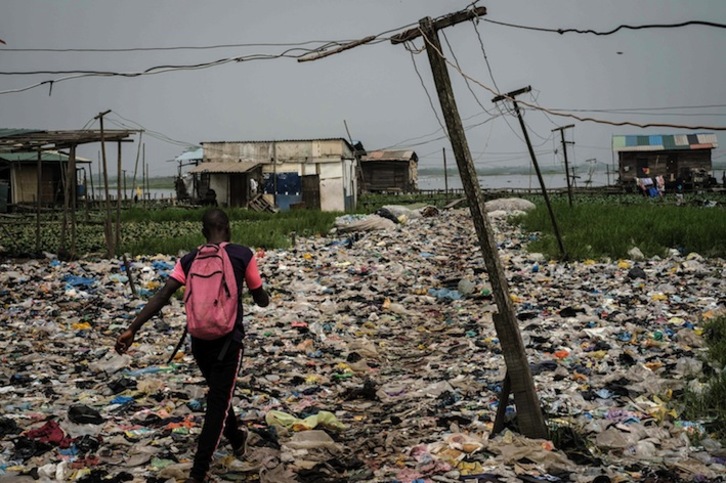 Un joven camina por un camino lleno de restos plásticos en Mosafejo, en Lagos. (Yasuyoshi CHIBA / AFP)