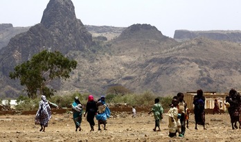 Varias personas caminan por la devastada por la guerra localidad de Golo, en Darfur. (AFP)