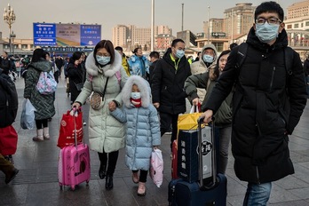 Cuidadanos chinos se protejen con mascarillas cerca de la estación de tren de Pekin. (Nicolas ASFOURI / AFP)