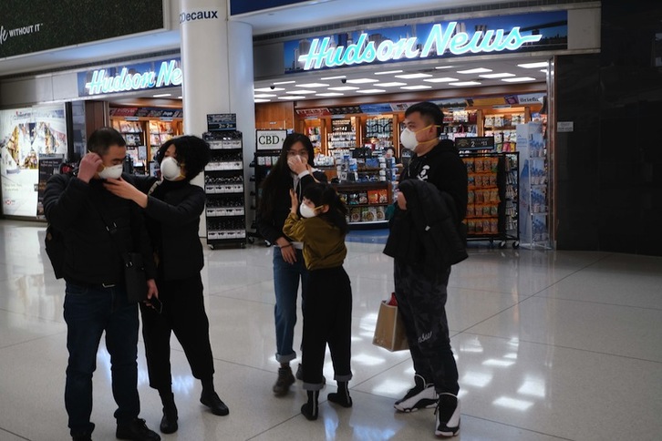 Personas con máscaras esperan un avión de China en el aeropuerto de Nueva York. (Spencer PLATT | AFP)