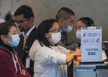 Pasajeros con mascarilla en un mostrador del aeropuerto de California para comprar billetes de avión para Shanghai. (Mark RALSTON/ AFP)