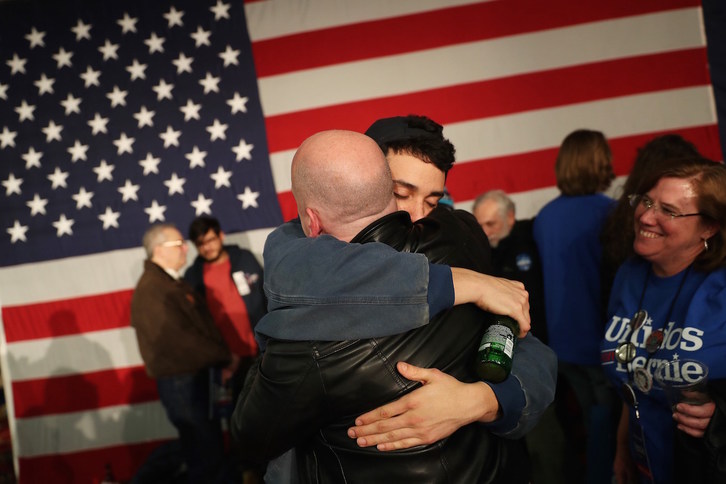 Partidarios de Bernie Sanders se abrazan en Des Moines tras notificarse el retraso en la proclamación de los resultados. (Joe RAEDLE/GETTY IMAGES-AFP)