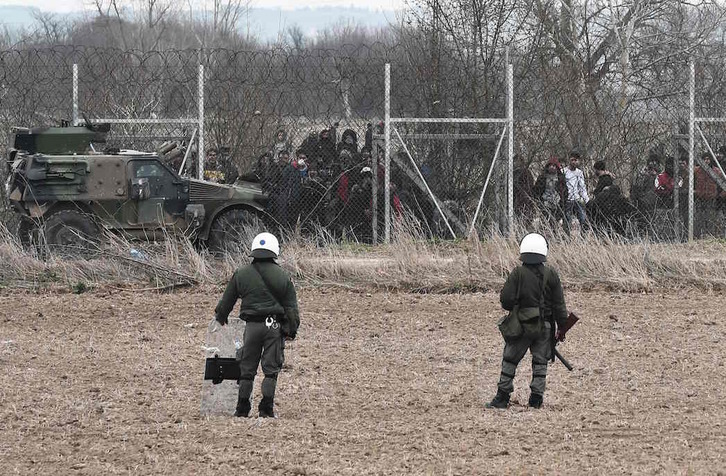 Soldados griegos frente a un grupo de migrantes, en la frontera con Turquía. (Sakis MITROLIDIS / AFP)