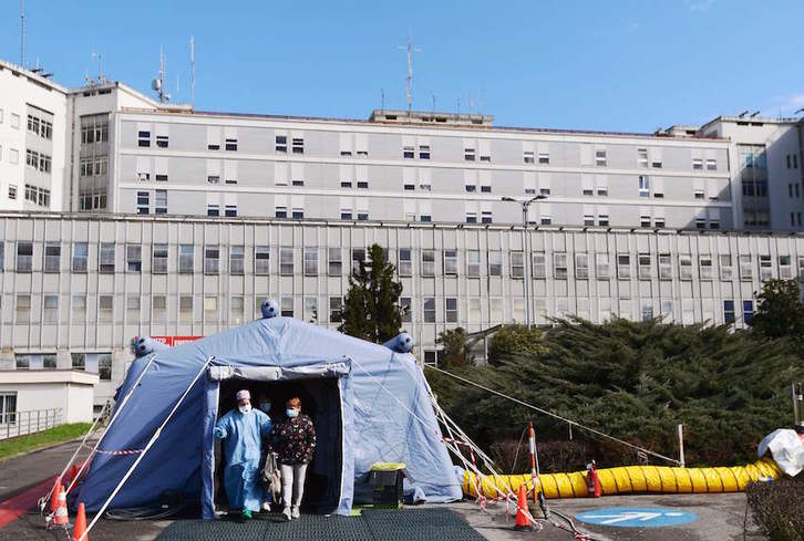 Una mujer sale de un hospital de campaña instalado en el exterior del hospital de Cremona. (Miguel MEDINA/AFP)