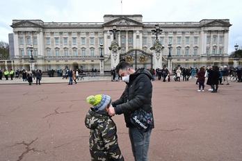 Un padre pone la mascarilla a su hijo frente al Palacio de Buckingham    (Glyn KIRK I AFP)