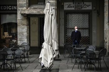 Un hombre con mascarilla ante un bar clausurado en la Piazza Palazzo di Citta. (Marco BERTORELLO/AFP)