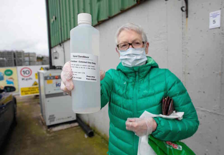 Una clienta muestra una botella de desinfectante comprada en la destilería de Listoke, al norte de Dublín. (Paul FAITH/AFP)