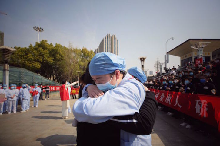 Abrazo de un sanitario sonriente en Wuhan. (AFP)