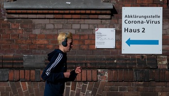 n joven pasa ante un cartel que dirige a la gente a uno de los centros habilitados en Berlín para realizar test de coronavirus. (John MACDOUGALL | AFP)