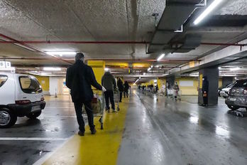 Clientes hacen cola con sus carritos en el parking de establecimiento comercial italiano. (Andreas SOLARO/AFP)