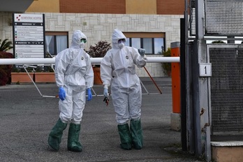 Doctoras con una máscara protectora y un mono de pie en la entrada del hospital de Nomentana en Fonte Nuova-Tor Lupara, cerca de Roma. (Tiziana FABI /AFP)