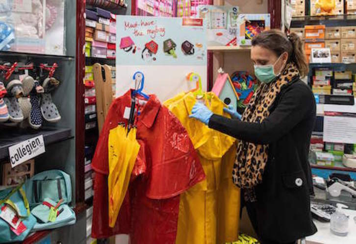Una empleada ordena el género de su tienda de ropa, alguno de los establecimientos que han reabierto sus puertas en Roma.(Tiziana FABI/AFP)