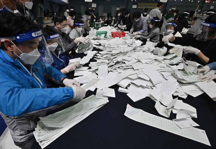 Operarios vacían las urnas tras la votación. (HUNG Yeon-je | AFP)