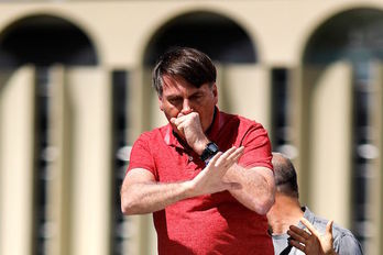 Bolsonaro, tapándose la boca tras toser en la marcha de Brasilia. (Sergio LIMA / AFP)