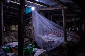 Un comerciante duerme en un mercado de Kampala (Uganda) con una mosquitera para progerse de la malaria. (Badru KATUMBA | AFP)