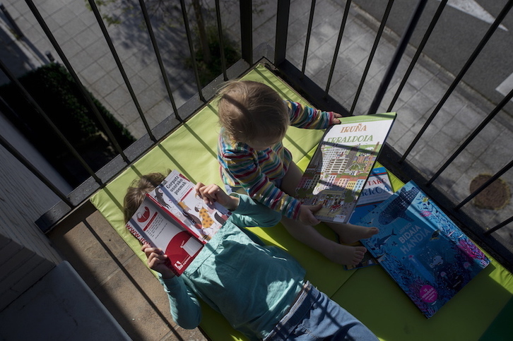 Dos niños leen libros en el balcón de su casa. (Iñigo URIZ/FOKU)