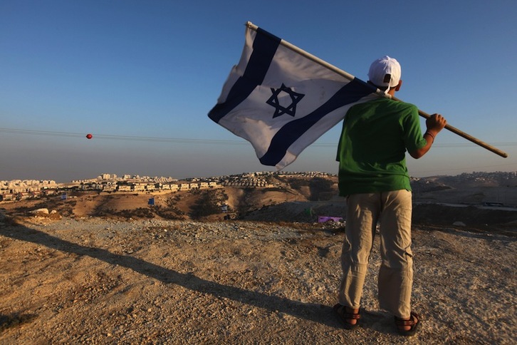 Un israelí agita su bandera con la vista puesta en la colonia de Maale Adumim, en Jerusalén Oriental. (MENAHEM KAHANA  | AFP)