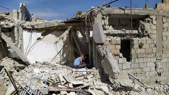 Dos jóvenes sentados entre los escombros de un edificio de Damasco tras un bombardeo de Israel el 27 de abril. (AFP)