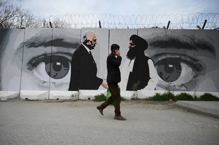 Un hombre pasa ante un mural que representa al enviado de EEUU para la reconciliación, Zalmay Khalilzad, y al confundador del movimiento talibán, mullah Abdul Ghani Baradar. (Wakil KOHSAR / AFP)