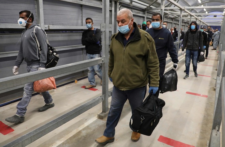 Trabajadores palestinos que trabajan en Israel cruzan el puesto de control de Mitar en la ciudad ocupada de Cisjordania de Hebrón. (Hazem BADER/AFP)