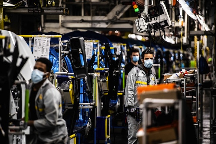 Empleados trabajan a lo largo de la línea de ensamblaje que produce tanto el vehículo eléctrico Renault Zoe. (Martin BUREAU/AFP)