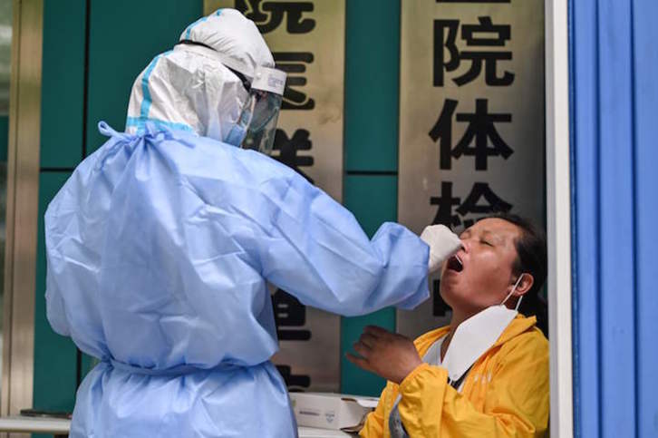 Un sanitario toma muestras para el test a una mujer en Wuhan. (Héctor RETAMAL/AFP)