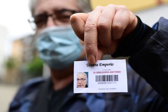 Antonio DiGregorio, desempleado que sobrevive con 400 euros mensuales, muestra la tarjeta con la que accede a un «supermercado» de Cáritas. (Miguel MEDINA/AFP)