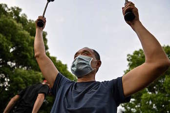 Un ciudadano chino realiza ejercicio protegido con su mascarilla. (Héctor RETAMAL/AFP)