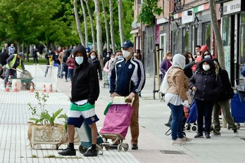 Gente haciendo cola ante el local en el que la Asociación de Vecinos de Aluche reparte comida gratis, en Madrid. (Javier SORIANO | AFP)