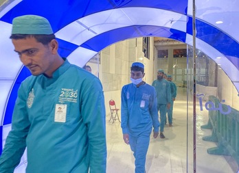 Trabajadores pasan por una puerta de esterilización instalada en una de las entradas a la Gran Mezquita de La Meca. (AFP)