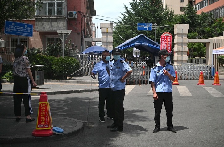 Personal de seguridad controla el acceso a un área residencial creca del mercado de Yuquang, en Pekín. (Noel CELIS | AFP)