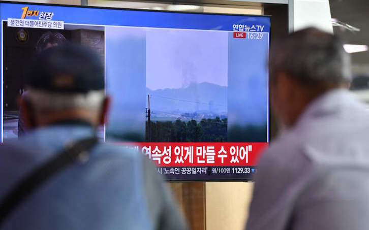 Dos hombres ven en televisión imágenes de una columna de humo en la zona de Kaesong. (JUNG YEONG-JE/AFP)