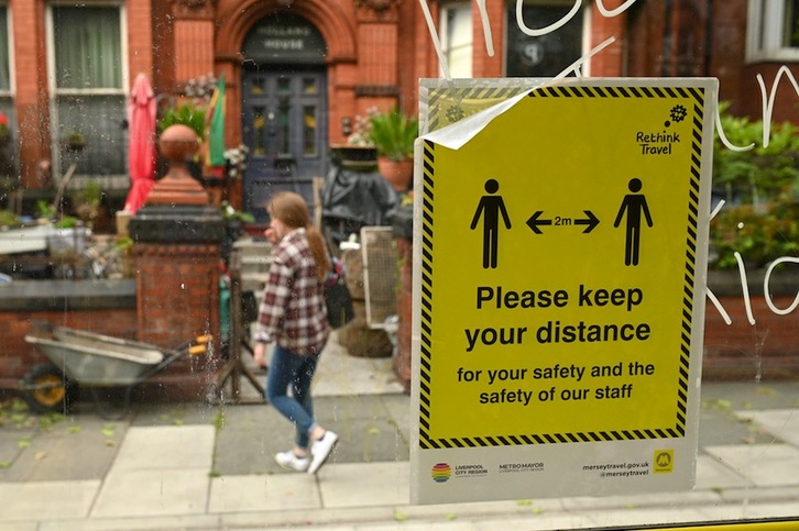 Un cartel colocado en una parada de bus de Liverpool recuerda que hay que mantener la distancia de seguridad. (Oli SCARFF | AFP)