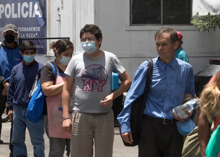 Un grupo de personas hace cola para recibir alimentos de un camión instalado junto al Centro Médico Nacional La Raza, en Ciudad de México. (Claudio CRUZ/AFP)