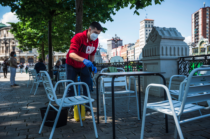 Un trabajador limpia la mesa de una terraza en Bilbo. (Aritz LOIOLA/FOKU).