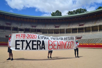 Los activistas despliegan la pancarta en apoyo a los presos y los refigudos en el coso de la plaza de toros de Iruñea. (SORTU IRUÑA)