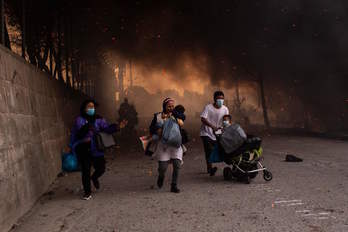 Refugiados en Moria huyen con sus hijos tras declararse el segundo incendio. (Angelos TZORTZINIS/AFP)