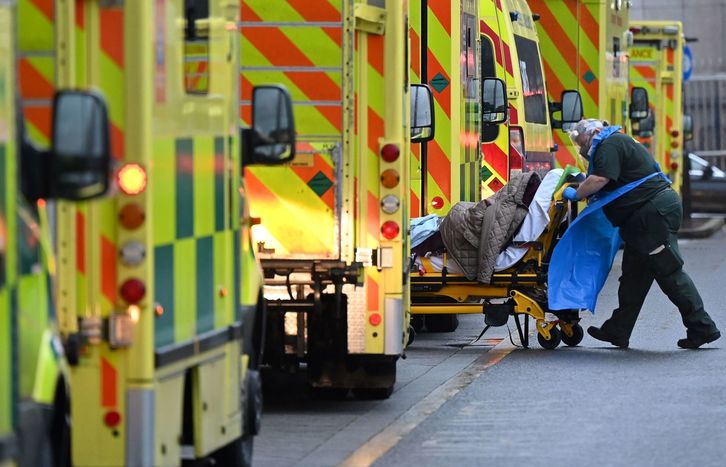 Un profesional sanitario traslada a un paciente entre ambulancias del Royal London Hospital.    (Justin TALLIS I AFP)