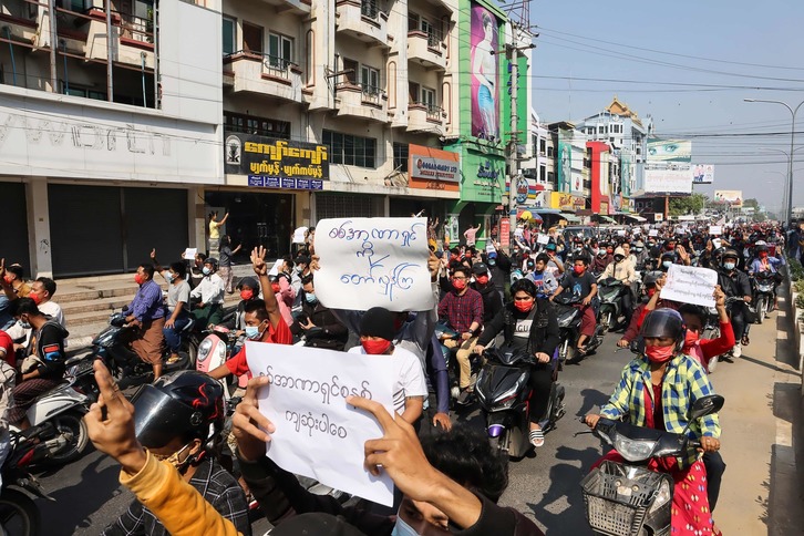 Manifestantes sostienen carteles contra el golpe militar cerca del palacio real en Mandalay. (STR/AFP)