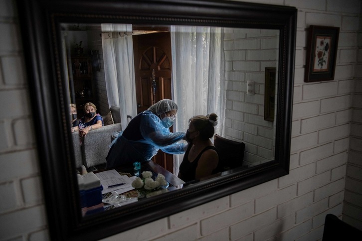 El espejo refleja a una enfermera mientras inocula la vacuna contra el covid-19 a una mujer en su domicilio de Santiago, la capital de Chile. (Martín BERNETTI | AFP)