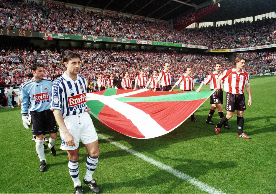 Athletic eta Realeko jokalariak San Mameseko zelaia zapaltzen ikurrina eskuetan dutela (1999-04-04). (Luis JAUREGIALTZO/FOKU)