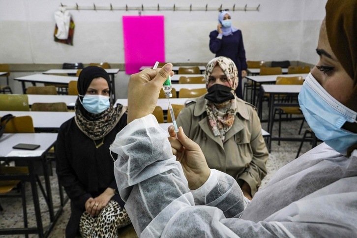 Una sanitaria palestina prepara una dosis de AstraZeneca para ser administrada en una escuela de Hebrón. (Hazem BADER | AFP)