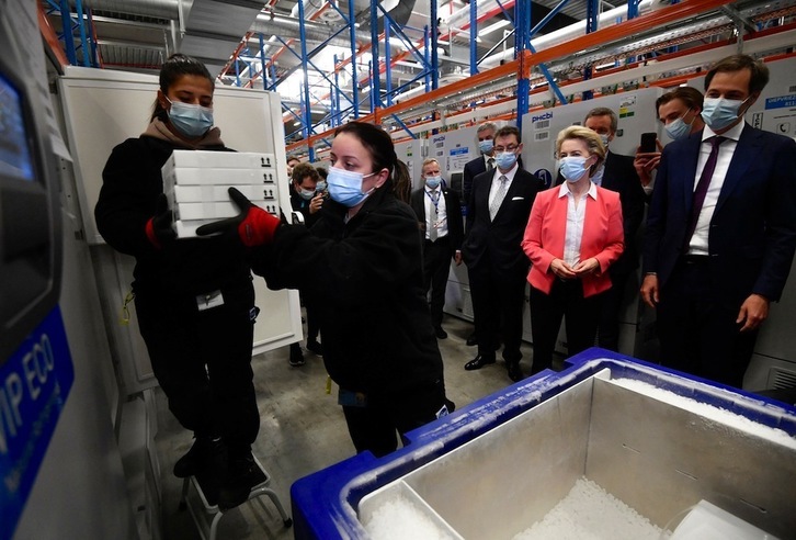La presidenta de la Comisión Europea, Ursula von der Leyen, observa a las trabajadoras que sacan cajas de vacunas en la fábrica de Pfizer en Puurs. (John THYS | AFP)