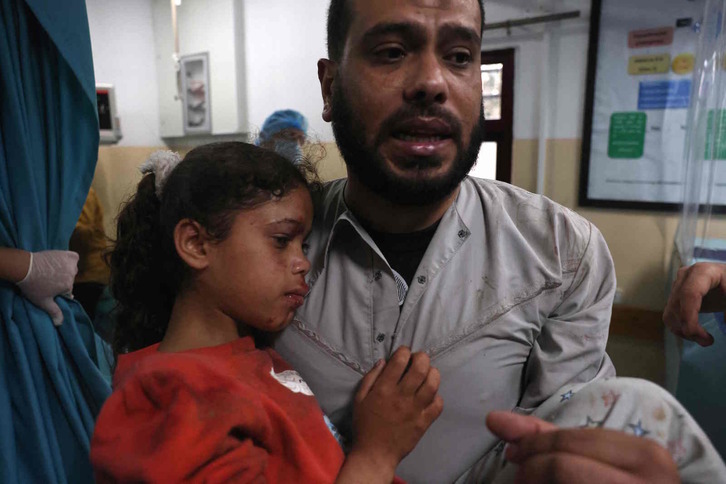 Un hombre lleva en brazos a una niña herida en el ataque contra Gaza. (Mohammed ABED/AFP)